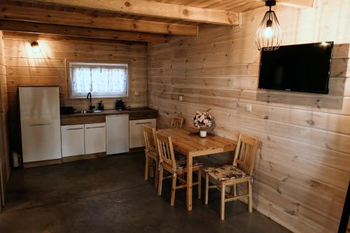a kitchen with a wooden wall with a table and chairs at Mazurski Ośrodek Szych in Bogusze
