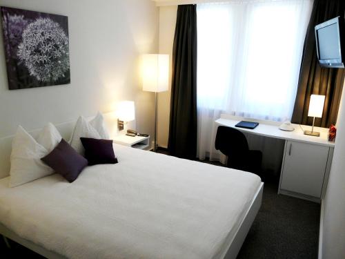 ein Hotelzimmer mit einem weißen Bett und einem Schreibtisch in der Unterkunft Fontana Budget in Twann