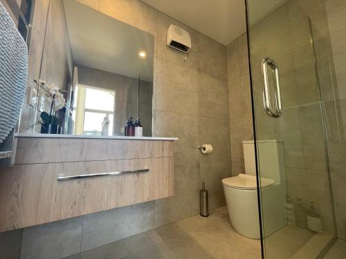 a bathroom with a toilet and a glass shower at Inner City Luxury With Free Parking in Christchurch