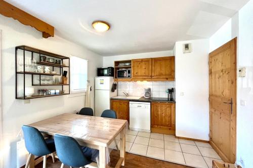 une cuisine avec une table en bois et des chaises bleues dans l'établissement LUMINEUX 43 m avec 2 BALCONS près des Pistes, à Saint-Gervais-les-Bains