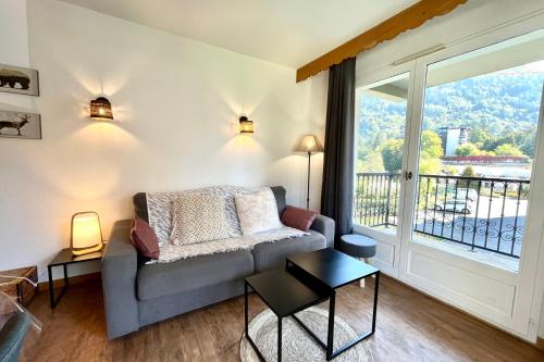 un salon avec un canapé et une grande fenêtre dans l'établissement LUMINEUX 43 m avec 2 BALCONS près des Pistes, à Saint-Gervais-les-Bains