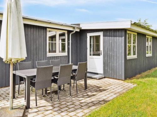 un patio con mesa, sillas y sombrilla en 6 person holiday home in F rvang, en Fårvang