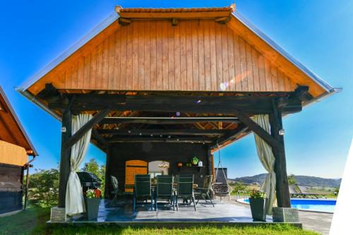 a wooden pavilion with chairs and a table at Holiday Home BIBA With Heated Outdoor Pool in Gornja Stubica