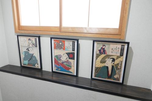four framed pictures on a shelf under a window at Lodging Tokyo Shibamata in Tokyo