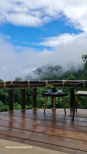 a table on a deck with a view of the mountains at สวนส่อผ่า&ฟาร์มสเตย์ in Mae Sai