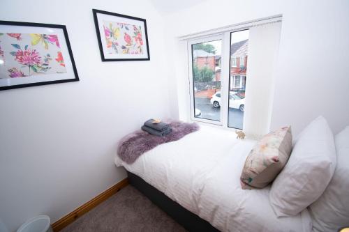 een woonkamer met een witte bank en een raam bij Ideal Lodgings in Bury - Redvales in Bury