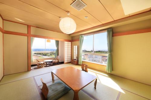 a living room with a table and a large window at Boso Shirahama Umisato Hotel in Minamiboso