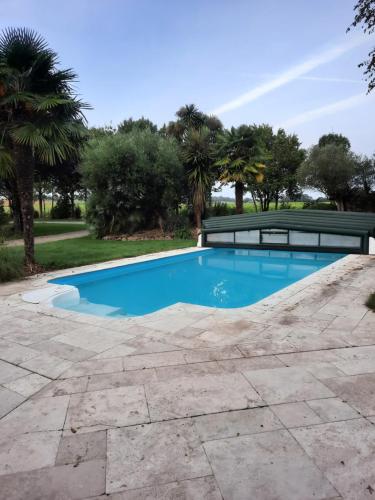 a swimming pool with a stone walkway around it at Chambre à louer in Goven