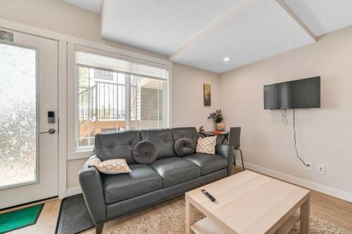 a living room with a black leather couch and a table at Brand New Executive Suite in Calgary