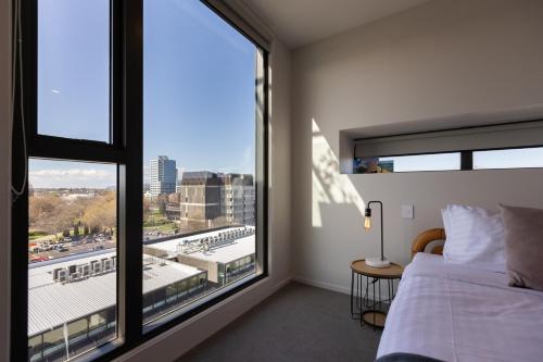 a bedroom with a bed and a large window at Luxury 2 Bedroom CBD Apartment with Free Parking in Christchurch