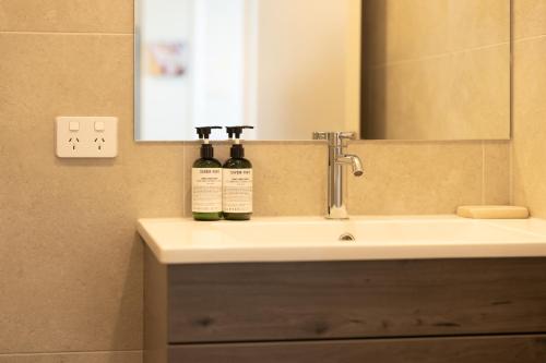 two bottles of wine sitting on a bathroom sink at Luxury 2 Bedroom CBD Apartment with Free Parking in Christchurch