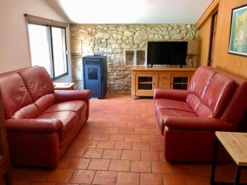 a living room with two leather couches and a flat screen tv at Gite de charme en pierres apparentes : Les Granges in Gardonne