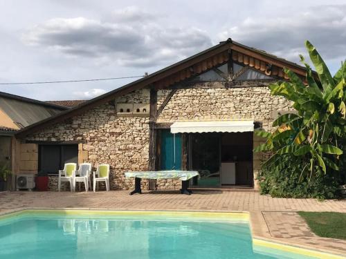 a house with a pool and a table and chairs at Gite de charme en pierres apparentes : Les Granges in Gardonne