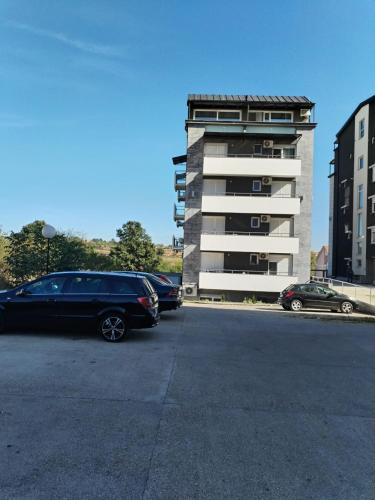 Un estacionamiento con autos estacionados frente a un edificio. en Bella apartman, en Mladenovac