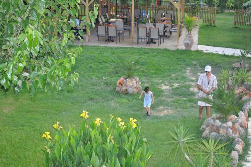 a man and a little girl walking through a yard at Olympion Village Studios in Zakharo