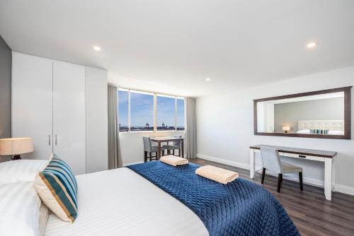 Schlafzimmer mit einem Bett, einem Schreibtisch und einem Spiegel in der Unterkunft The Allegra - 180 degree ocean and city views in Fremantle