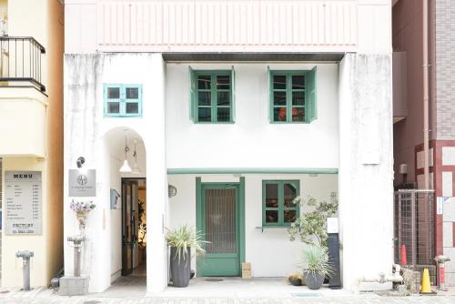 a white house with green doors and windows at Lodging Tokyo Ueno in Tokyo