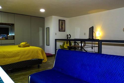 1 dormitorio con 1 cama y 1 sofá azul en Acogedor y moderno Loft en Cholula, en Santa María Tonantzintla