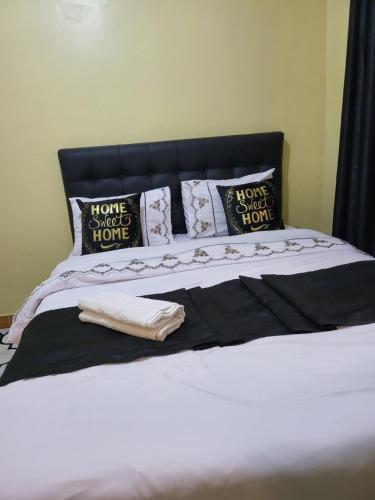 a bed with black and white pillows on it at G&G Homes Eldoret in Eldoret