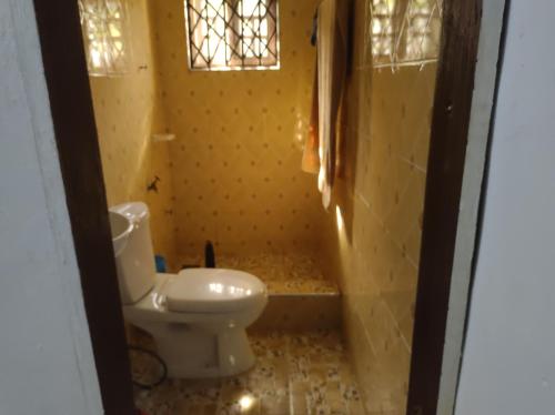 ein kleines Bad mit einem WC und einem Fenster in der Unterkunft Kingee Lodge in Sunyani