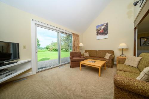 a living room with a couch and a tv and a table at Stoweflake Mountain Resort & Spa in Stowe
