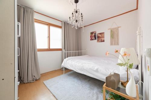 a bedroom with a white bed and a chandelier at Hapjeong station exit7 modern house in Seoul