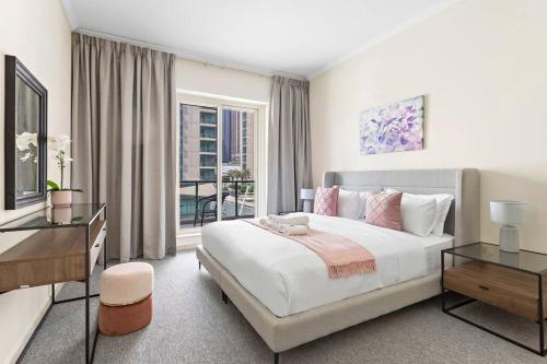 a white bedroom with a large bed and a balcony at StoneTree - Stylish 2BR with Dubai Marina Canal View in Dubai