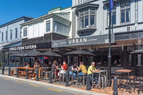 a group of people sitting at tables in front of a building at Inner City Apartments - 4 in Nelson