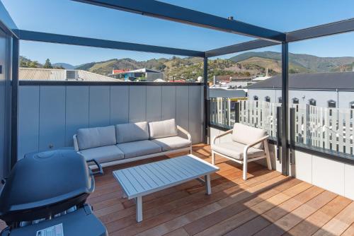 a patio with a couch and a chair on a balcony at Inner City Apartments - 4 in Nelson