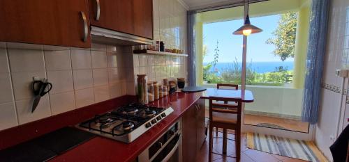 a kitchen with a stove and a counter with a window at Sunny Arco Retreat in Arco da Calheta