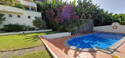 a swimming pool in a yard next to a building at Sunny Arco Retreat in Arco da Calheta