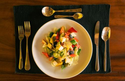 a plate of salad on a table with fork and knife at Chill House make a Good Story with infinite Ocean Surf and Stay in Weligama