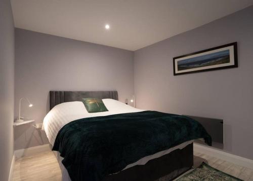 a bedroom with a large bed with a green blanket at Stay Indigo in Ballycastle