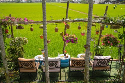 a garden with a table and chairs and flowers at Maison Fleur Luxury Hoi An in Hoi An