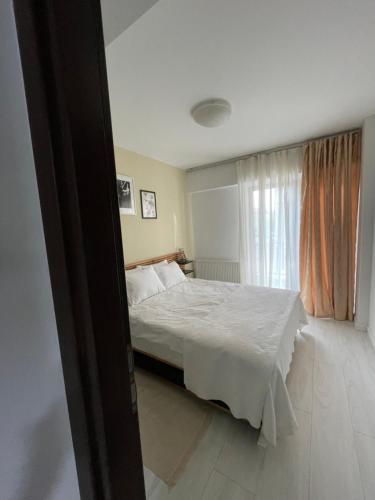 a bedroom with a white bed and a window at Apartament 2 camere Mogoșoaia in Mogoşoaia