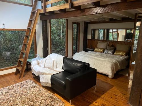 a bedroom with a bed and a chair and a ladder at Figtree Getaway in Malanda