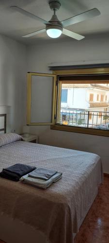 um quarto com uma cama, uma ventoinha de tecto e uma janela em Apartamento Urb Paraíso em Santa Pola
