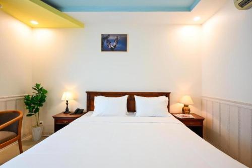 1 dormitorio con 1 cama blanca grande y 2 sillas en New Sunny 1 Hotel - Q7 by Bay Luxury, en Ho Chi Minh