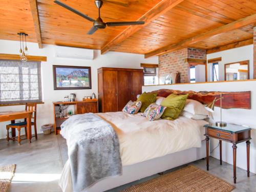 Duikersdrift Winelands Country Escape في تولباغ: غرفة نوم بسرير كبير وسقف خشبي