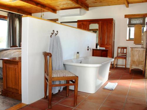 uma casa de banho com uma banheira, uma cama e uma cadeira em Duikersdrift Winelands Country Escape em Tulbagh
