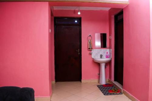 ein rosafarbenes Badezimmer mit einem Waschbecken und einer Mikrowelle in der Unterkunft EP Home in Meru