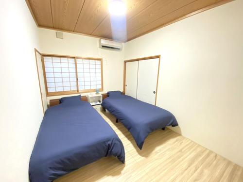 two beds in a room with blue sheets at 島の宿　結んちゅ in Amami