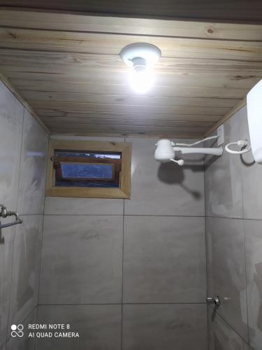 Baño con una pequeña ventana en el techo en Hospedaria Central - Hostel, en Bombinhas