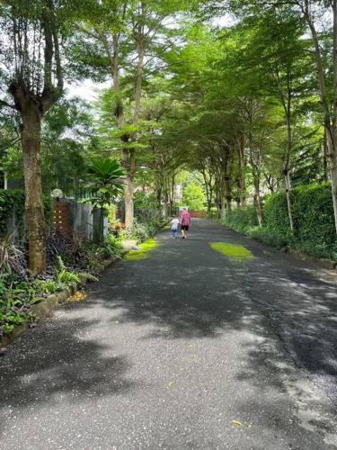 a woman and child walking down a road with trees at KhaoYai Treescape Retreat คอนโดบ้านชลธารเขาใหญ่ 2 ห้องนอน 2ห้องน้ำ 88ตารางเมตร ถนนธนะรัชต์ in Ban Tha Maprang