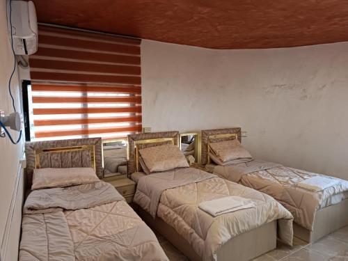 Zimmer mit 3 Betten und einem Fenster in der Unterkunft hostel ـ Karak dream in Kerak