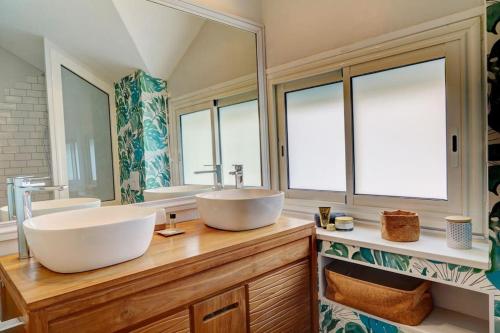 uma casa de banho com dois lavatórios e dois espelhos em NYLA Mango em Saint-Paul