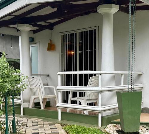 twee witte stoelen op een veranda van een huis bij Chandani Villa in Negombo
