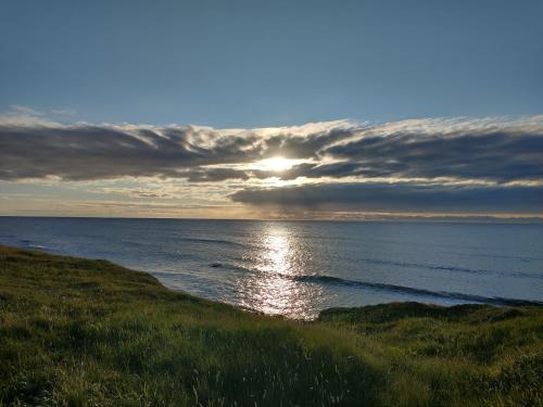 a sunset over the ocean with the sun shining at Snowberry Cottage in Borve