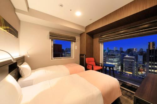 a hotel room with two beds and a window at S-peria Inn Osaka Hommachi in Osaka