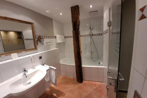 a bathroom with a tub and a sink and a shower at Hotel Goldene Sonne in Landshut